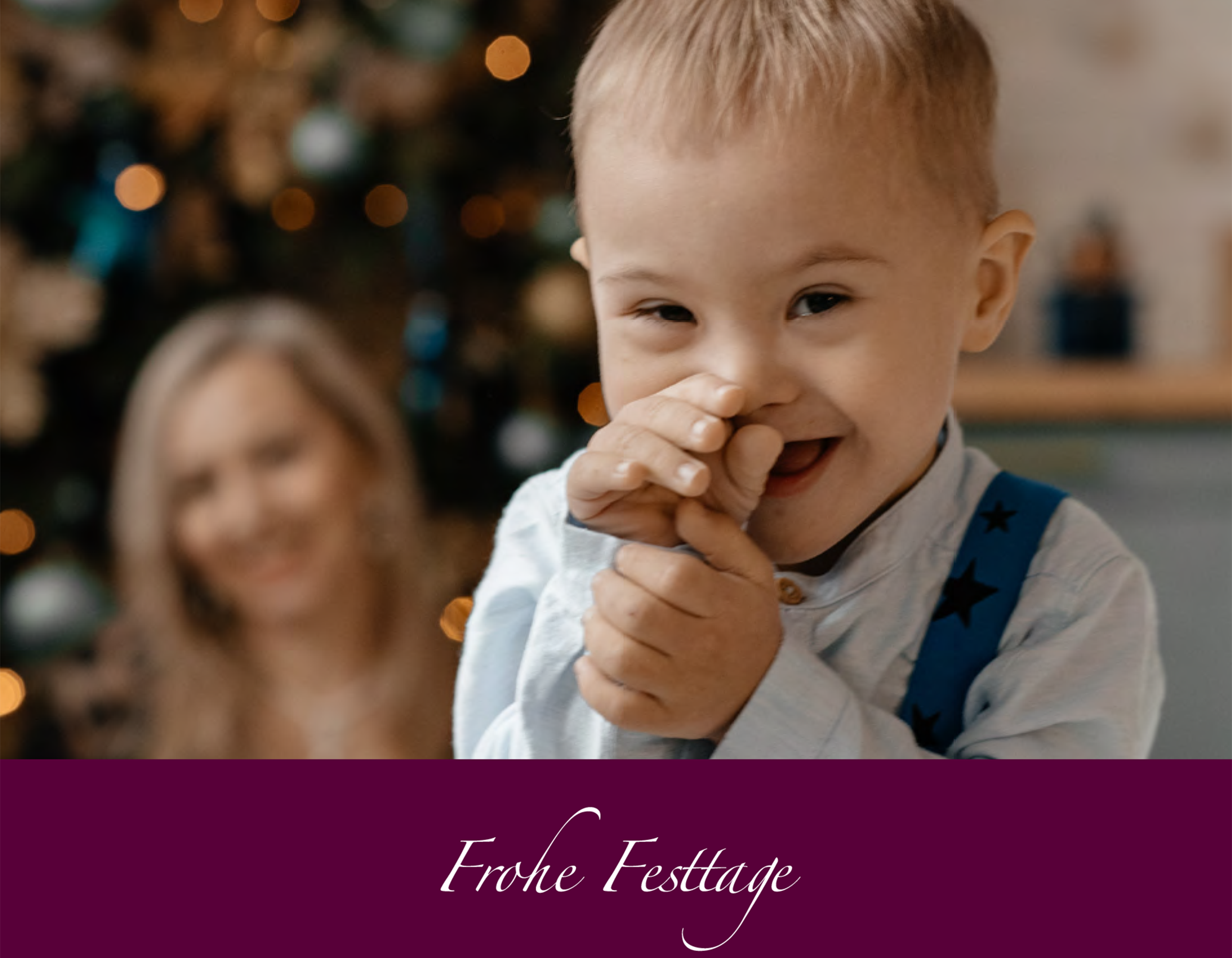 kleiner Junge mit Down-Syndrom vor einem Weihnachtsbaum