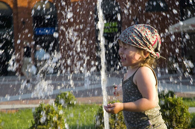 Kleinkind l&auml;uft durch Wasserstrahl