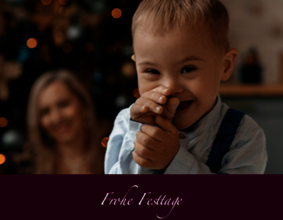 kleiner Junge mit Down-Syndrom vor einem Weihnachtsbaum